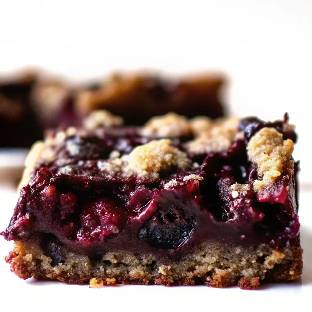Chocolate Chip Cherry Bars 9 Golden brown chocolate chip cherry bars cut into squares in a parchment-lined baking pan, showing melted chocolate chips and bright red cherry pieces throughout the chewy texture