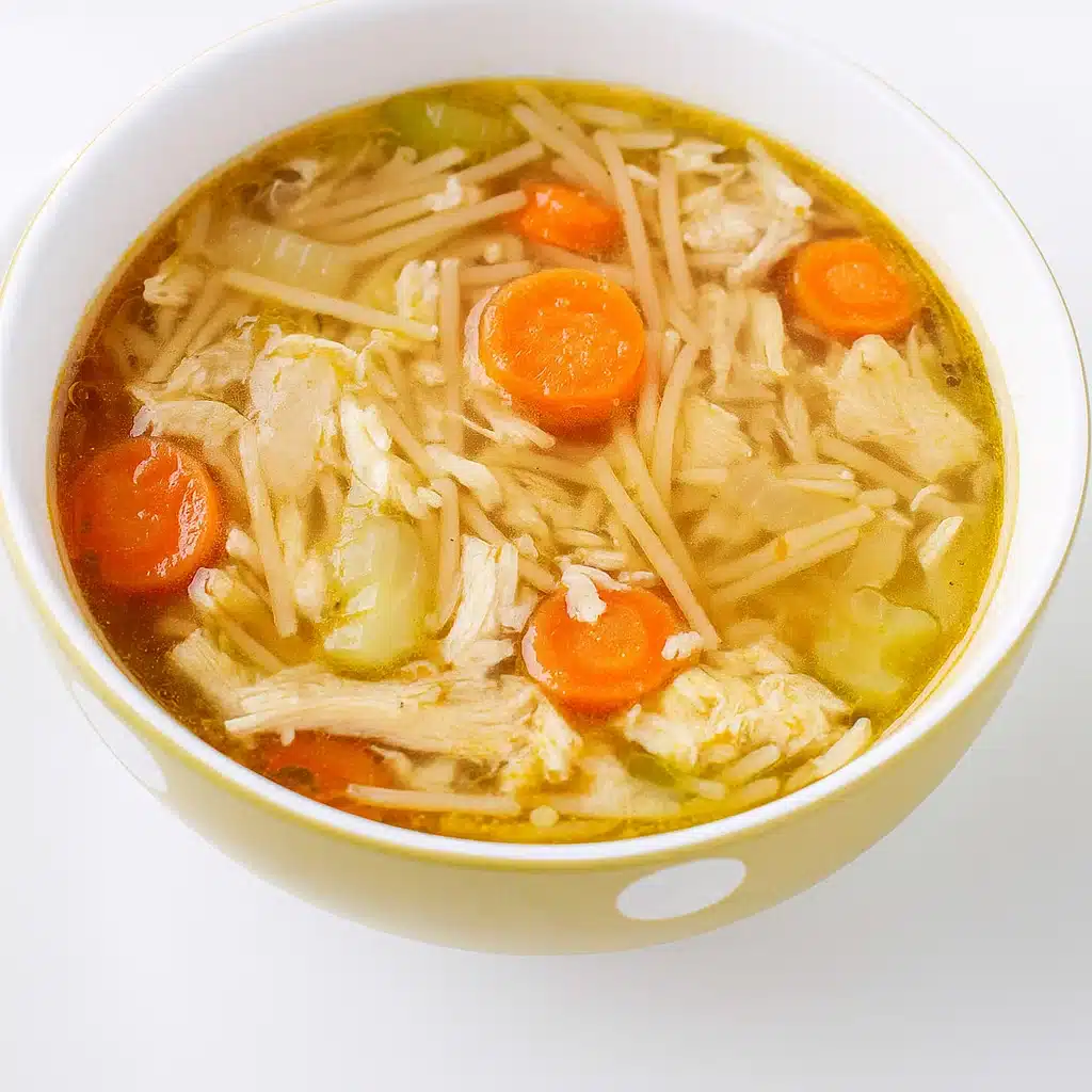 Crockpot Chicken Noodle Soup 6 A steaming bowl of homemade crockpot chicken noodle soup with tender shredded chicken, colorful vegetables, and wide egg noodles, garnished with fresh parsley