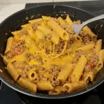 Creamy Rotel Pasta with Ground Beef 5 Creamy Rotel pasta with ground beef served in a white bowl, topped with fresh cilantro and melted cheddar cheese