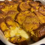 Golden baked pumpkin french toast casserole with crumb topping in a white baking dish