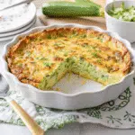 Easy Keto Crustless Zucchini Quiche 8 Golden brown keto crustless zucchini quiche with melted smoked Gouda cheese, garnished with fresh chives, cooling in a white pie dish