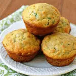 Healthy Banana Zucchini Muffins 10 Freshly baked banana zucchini muffins with golden tops cooling on a wire rack