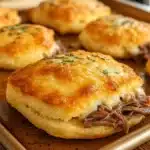 Easy Baked French Dip Biscuits 5 Baked French dip biscuits being dipped in rich au jus sauce