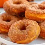 Easy Baked Pumpkin Donuts 8 Golden-brown baked pumpkin donuts with glossy maple glaze arranged on a wire cooling rack