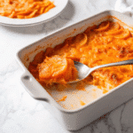 Golden-brown butternut squash casserole in a white baking dish, topped with melted mozzarella cheese and fresh basil garnish