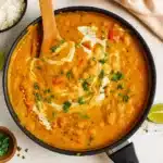 A bowl of creamy orange Indian pumpkin curry garnished with fresh cilantro and served with basmati rice, showing the rich, velvety texture and vibrant colors of this comforting one-pot meal.