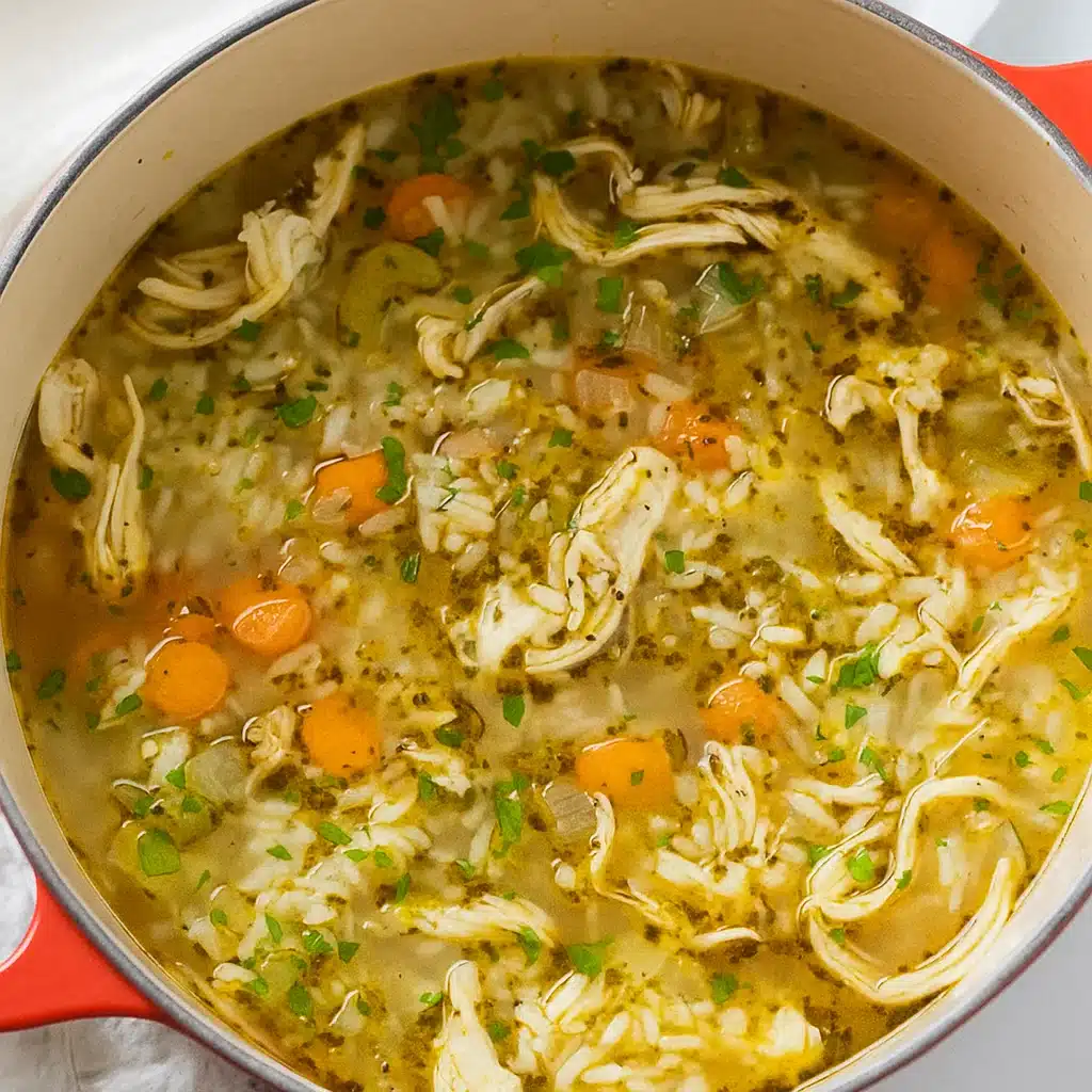 A steaming bowl of homemade chicken and rice soup with tender vegetables and shredded chicken in a rich, golden broth, garnished with fresh parsley