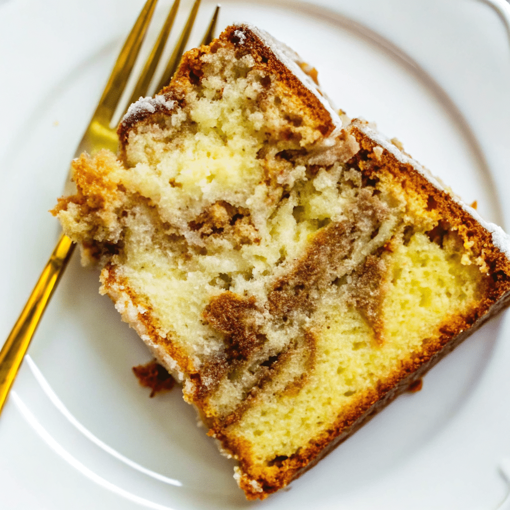 A slice of layered apple fritter cake on a white plate, showing moist yellow cake layers with chunks of cinnamon apples and brown sugar swirls, topped with white glaze dripping down the sides.