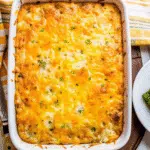 Golden breakfast butter swim biscuits in square baking dish with melted butter bubbling around edges, loaded with breakfast sausage and cheddar cheese