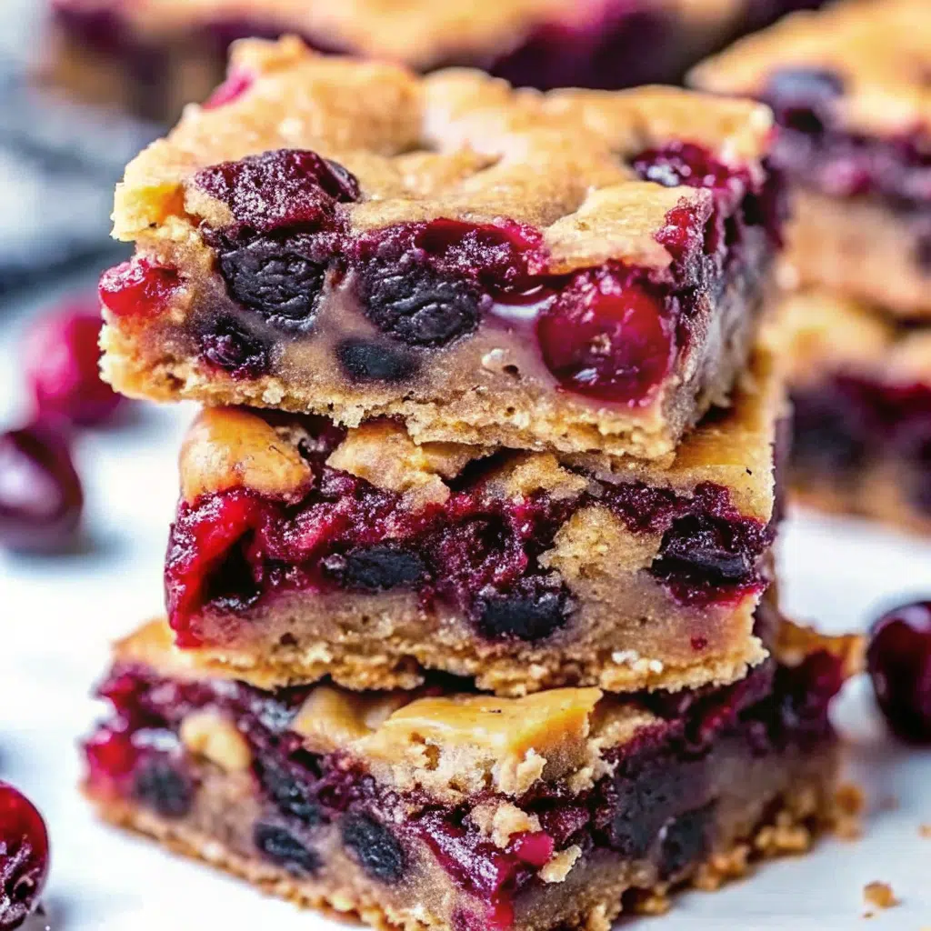 Golden brown chocolate chip cherry bars cut into squares in a parchment-lined baking pan, showing melted chocolate chips and bright red cherry pieces throughout the chewy texture