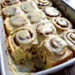 Apple Pie Cinnamon Rolls 8 Freshly baked apple pie cinnamon rolls in a baking dish, topped with cream cheese frosting and showing the spiral of cinnamon and apple filling