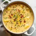 Outback Steakhouse Potato Soup 6 Creamy Outback Steakhouse Potato Soup in white bowl topped with melted cheddar cheese, bacon bits, and green onions, with steam rising from the surface