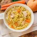 CopyCat Panera Bread Chicken Noodle Soup 5 A steaming bowl of homemade Panera Bread Chicken Noodle Soupwith tender shredded chicken, egg noodles, carrots, and celery in a rich golden broth, garnished with fresh herbs