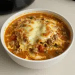 One Pot Lasagna Soup 5 A steaming bowl of one pot lasagna soup topped with melted mozzarella, Parmesan, and a dollop of ricotta cheese, with broken lasagna noodles visible in the rich tomato broth.