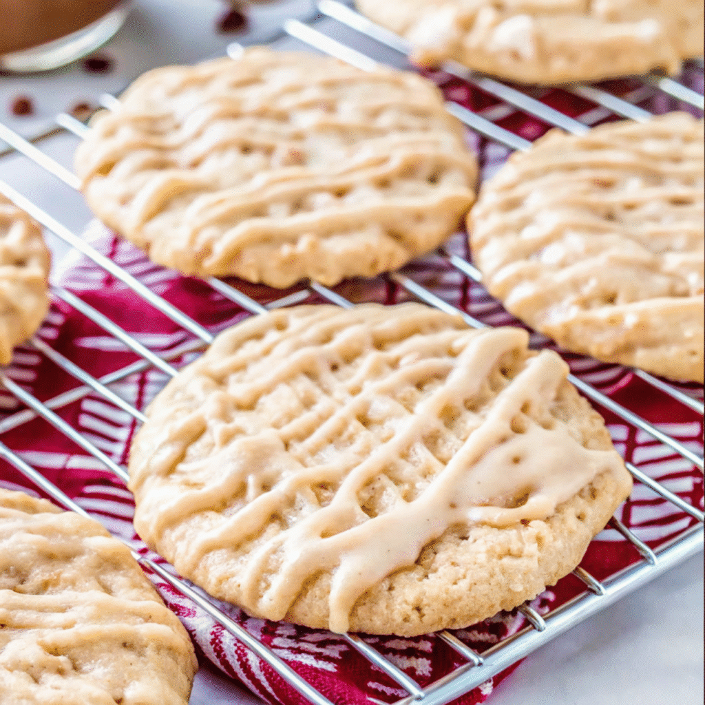 Soft and chewy apple cider cookies with visible apple chunks, drizzled with cinnamon apple cider glaze on a wire cooling rack