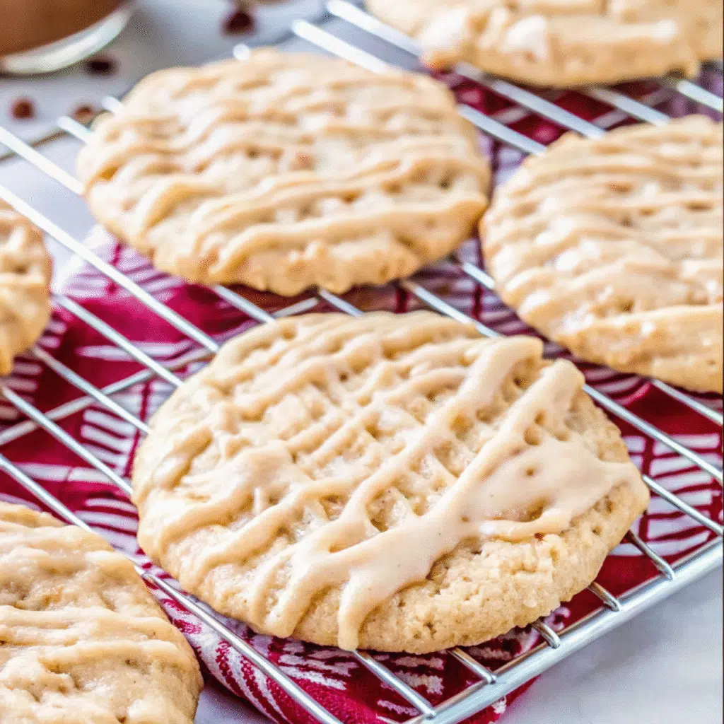 Soft and chewy apple cider cookies with visible apple chunks, drizzled with cinnamon apple cider glaze on a wire cooling rack