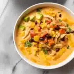 Chicken Taco Soup 5 Bowl of creamy chicken taco soup with cheese, avocado, cilantro, lime wedges and tortilla chips