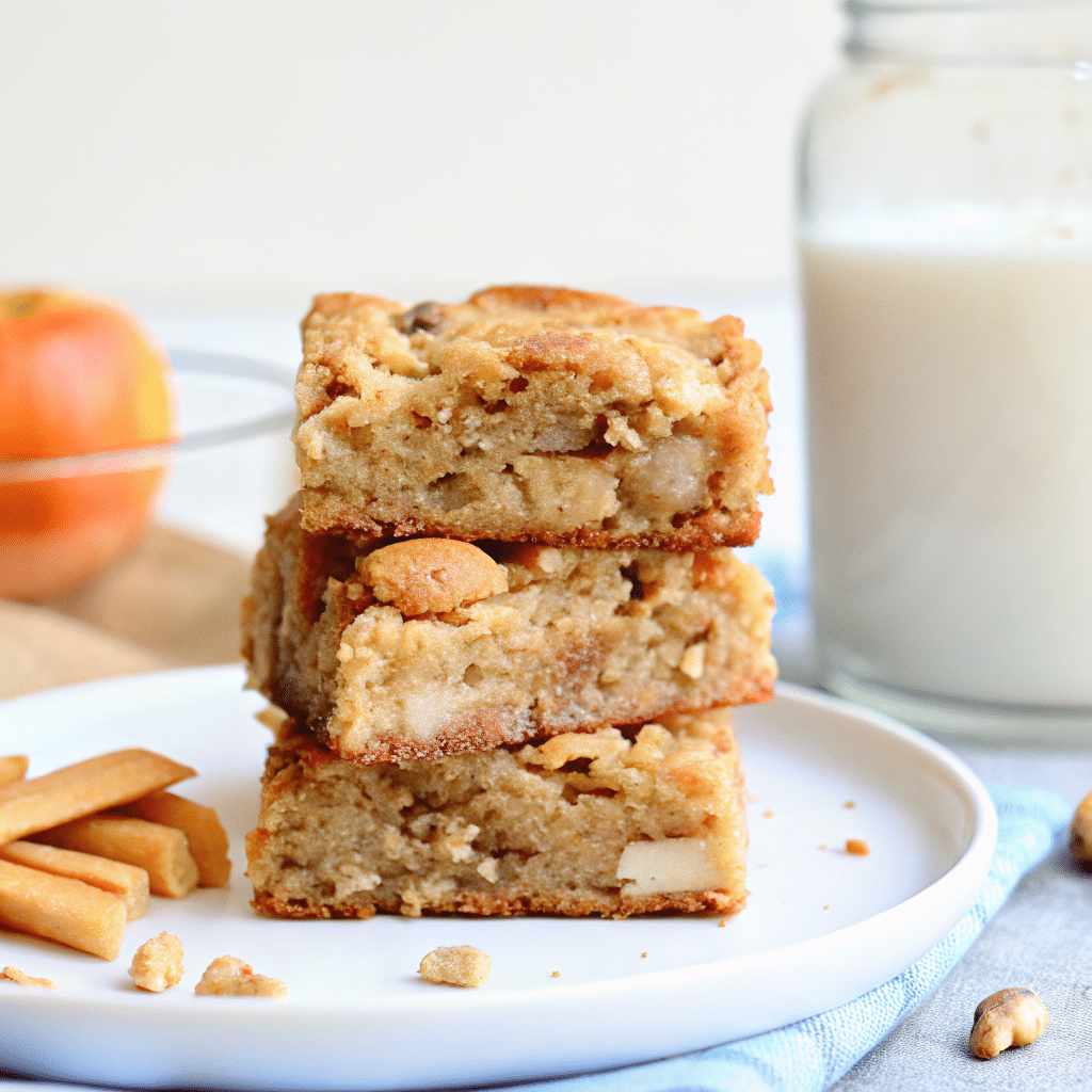 Square apple brownies golden edges visible tender apple chunks throughout topped cinnamon-sugar crystals cut neat squares arranged white ceramic plate rustic wooden background