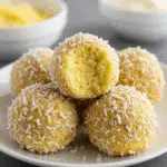 Easy pineapple Christmas balls coated in shredded coconut and served on a festive holiday plate.