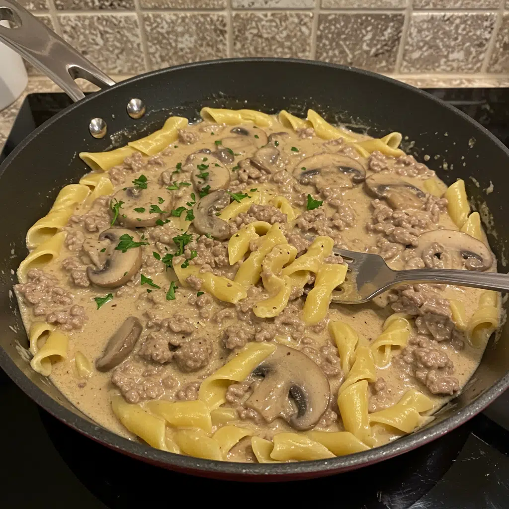 Creamy ground beef stroganoff in a skillet with tender mushrooms and rich sauce, served over egg noodles