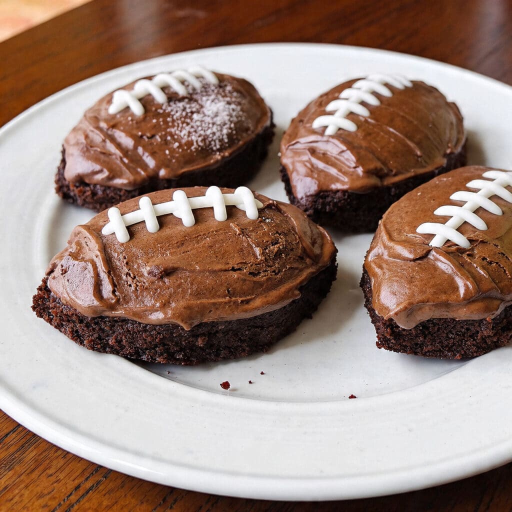 Rich fudgy football brownies decorated with white icing to look like football laces, arranged on a platter for a fun game-day treat.