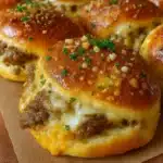 Golden-brown garlic parmesan cheeseburger bombs filled with juicy beef, melted cheese, and wrapped in soft biscuit dough, sprinkled with parmesan and parsley.