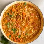 Bowl of golden orange sweet potato chickpea curry with fresh cilantro garnish served over fluffy white rice