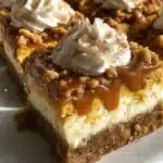 Pumpkin Spice Cheesecake Bars feature a buttery pecan graham cracker crust, creamy vanilla cheesecake layer, and spiced pumpkin layer topped with whipped cream