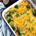 Low carb chicken casserole with melted cheese, broccoli, cauliflower rice, and crispy bacon in a white baking dish