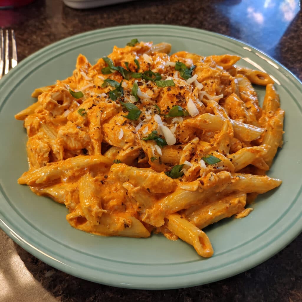 Buffalo Chicken Pasta coated in creamy buffalo sauce and topped with cheese and green onions.