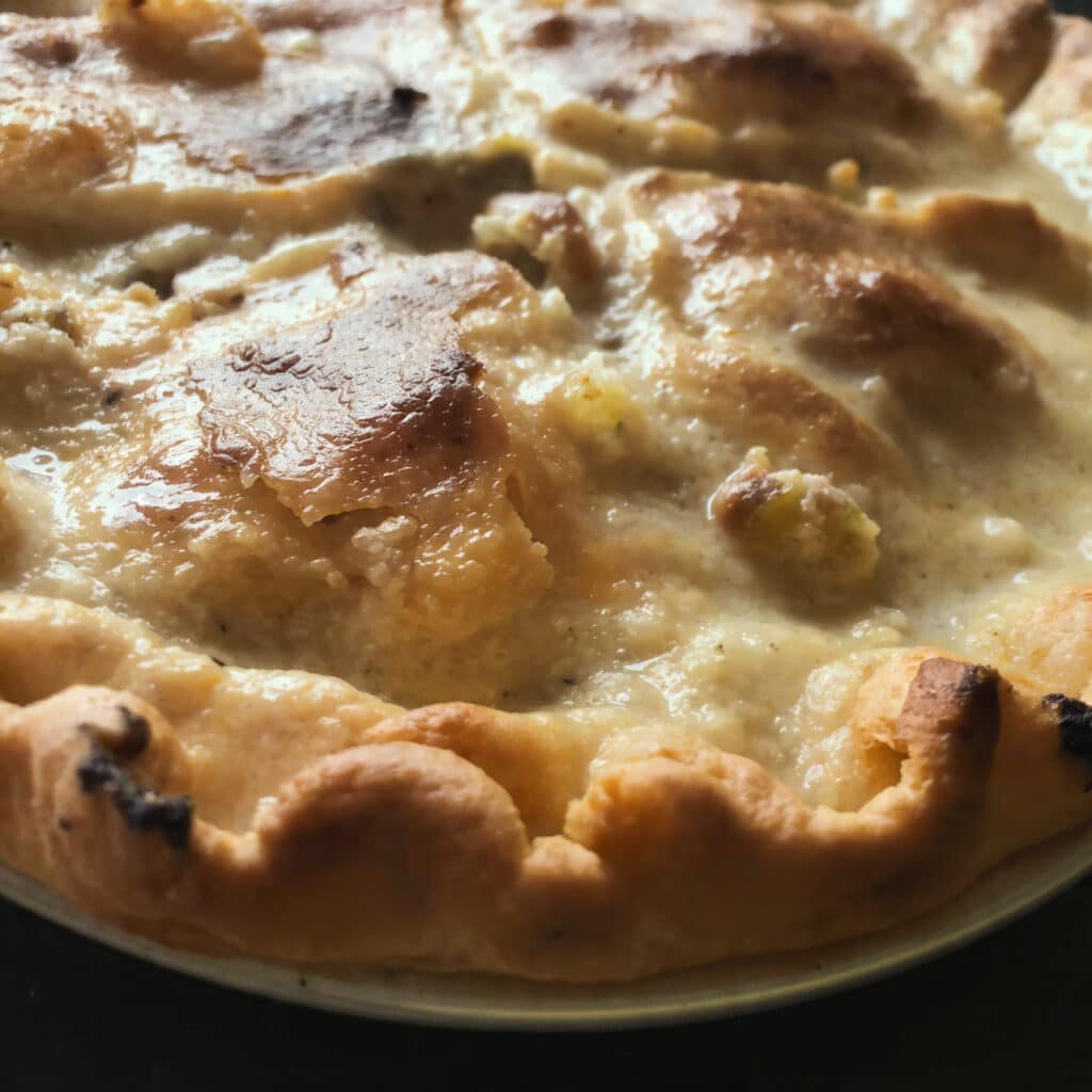 Golden-brown Mama's Chicken Pie in a square baking dish with latticed pie crust strips on top, creamy chicken filling visible between the layers