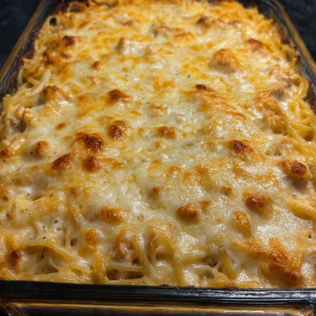 Chicken Spaghetti: The Cheesy, Creamy Casserole Everyone Begs For 6 golden casserole of chicken spaghetti with melted sharp cheddar cheese on top, fresh from the oven in a rectangular baking dish