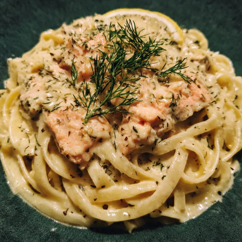 Creamy lemon dill salmon pasta with flaky chunks of salmon and fresh dill in a skillet