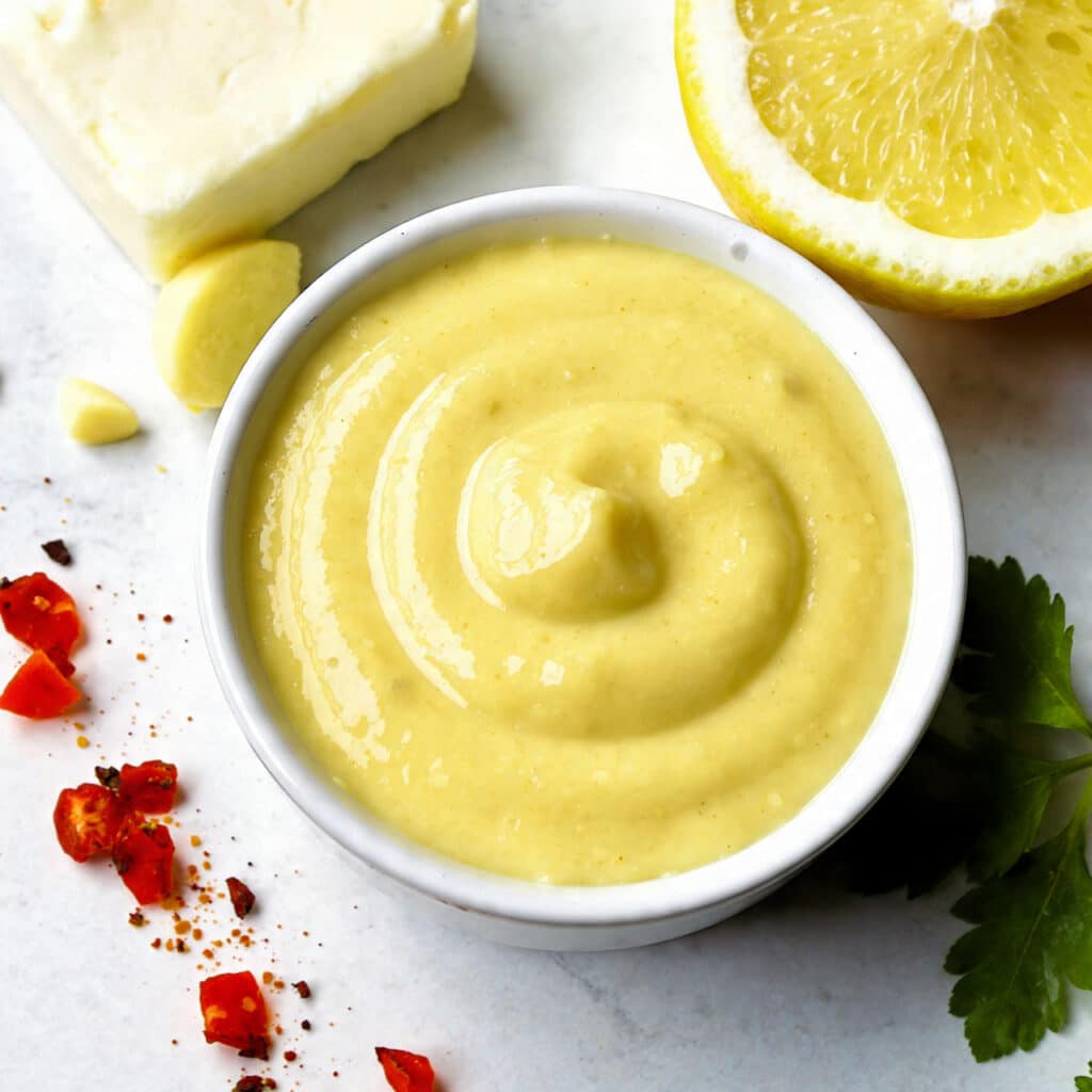 Silky lemon butter sauce poured over a dish and garnished with fresh lemon zest
