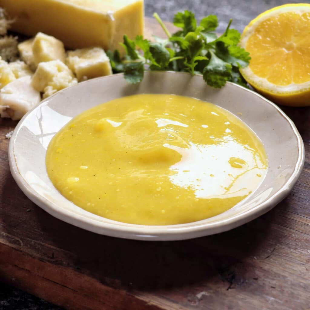 Silky lemon butter sauce poured over a dish and garnished with fresh lemon zest