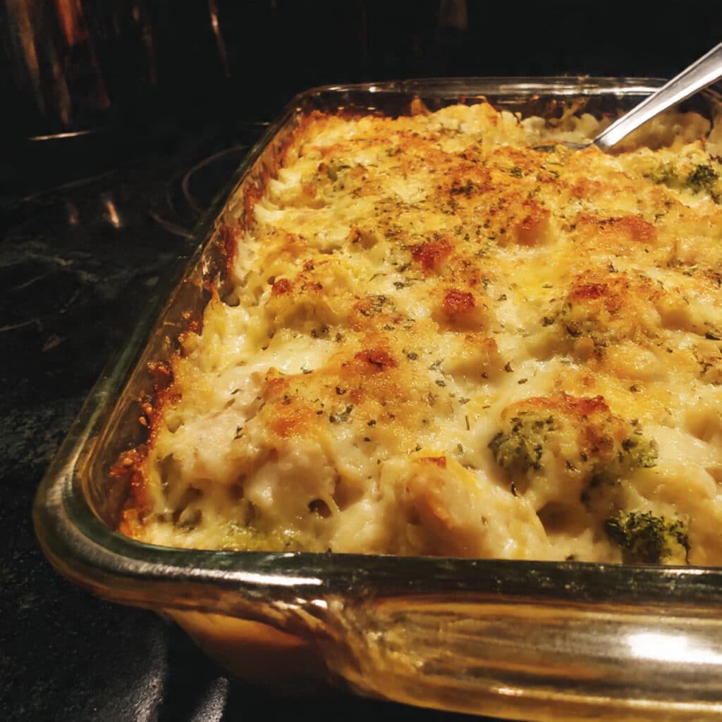 Creamy chicken divan casserole in a white baking dish with golden breadcrumb topping, melted cheese, tender broccoli florets, and chunks of chicken visible throughout