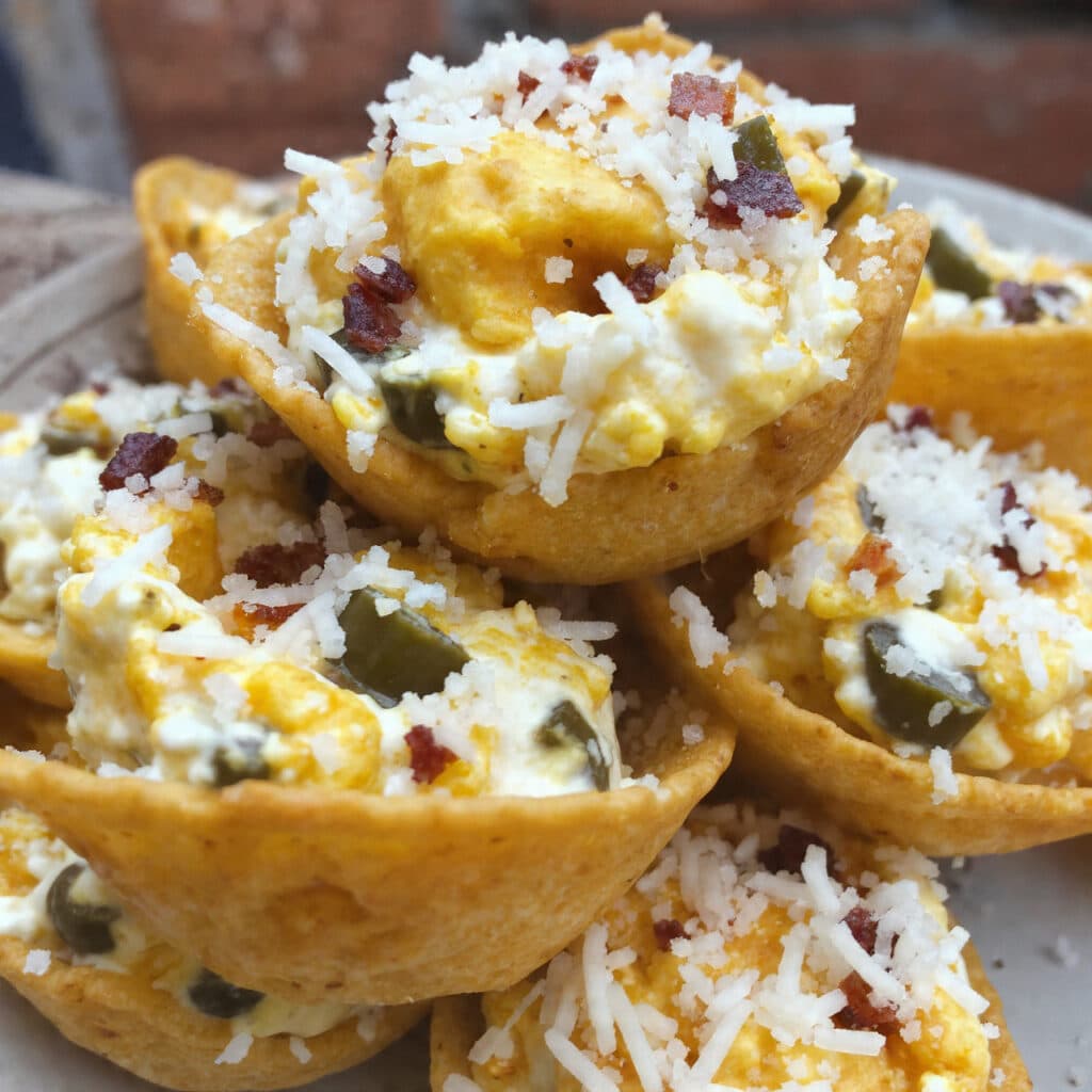 Golden-brown Playoff Puffs arranged on a white platter, featuring Tostitos Scoops filled with creamy jalapeño-bacon mixture topped with melted Parmesan cheese