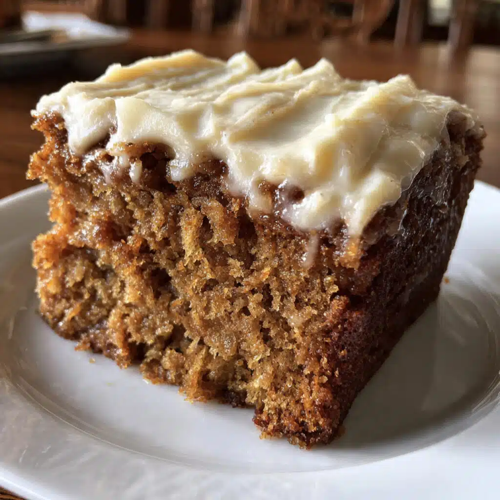 Slice of moist applesauce spice cake with cream cheese frosting on a white plate with a fork