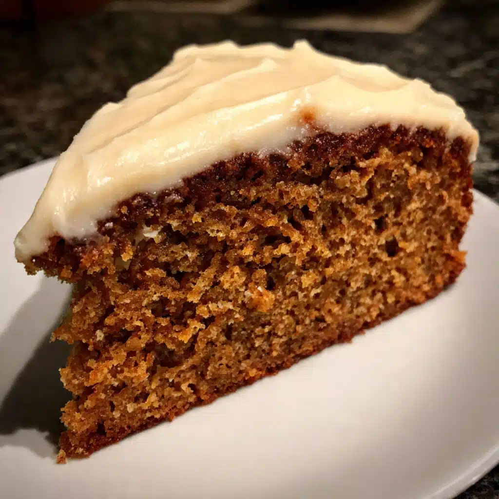 Slice of moist applesauce spice cake with cream cheese frosting on a white plate with a fork