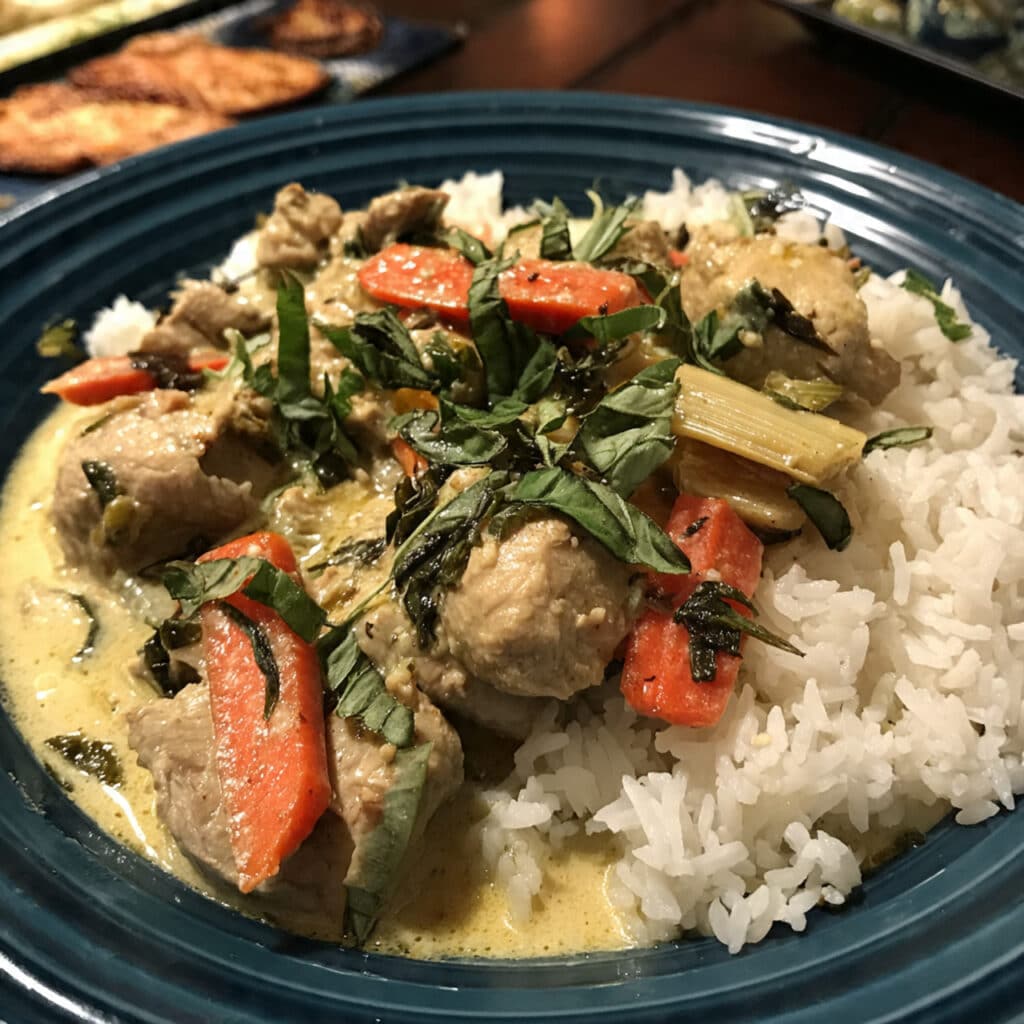 A bowl of vibrant green Thai curry chicken with tender chicken pieces, bamboo shoots, and fresh Thai basil leaves in creamy coconut sauce, served over steamed jasmine rice