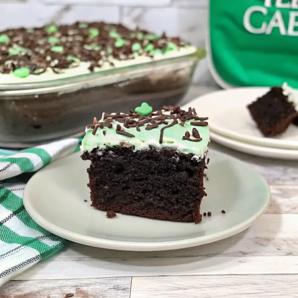 Slice of Andes Mint Poke Cake on white plate showing layers of chocolate cake, hot fudge, chocolate pudding, and mint whipped cream