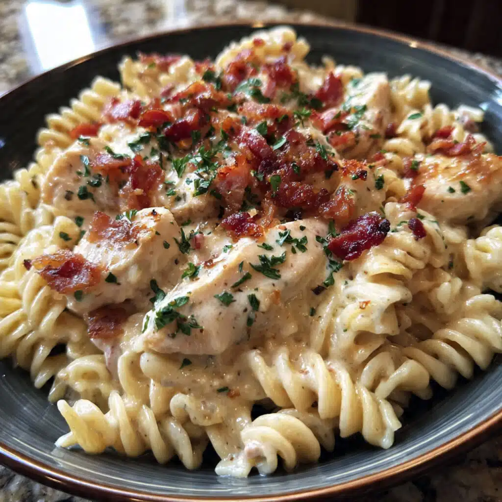 Creamy chicken bacon ranch pasta in a white bowl with melted cheese, crispy bacon pieces, and fresh parsley garnish