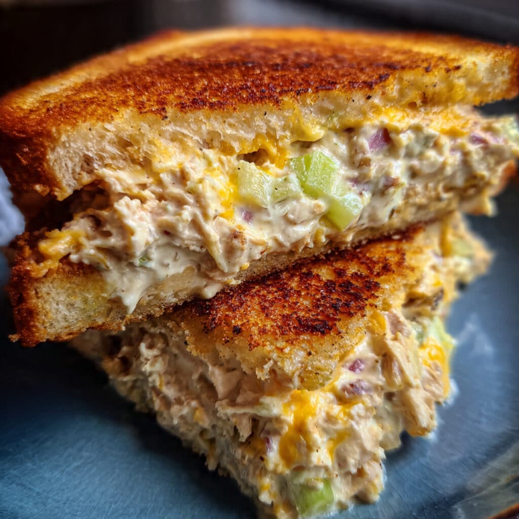 Golden brown tuna melt sandwich cut in half showing melted cheddar cheese and creamy tuna salad filling on toasted sourdough bread