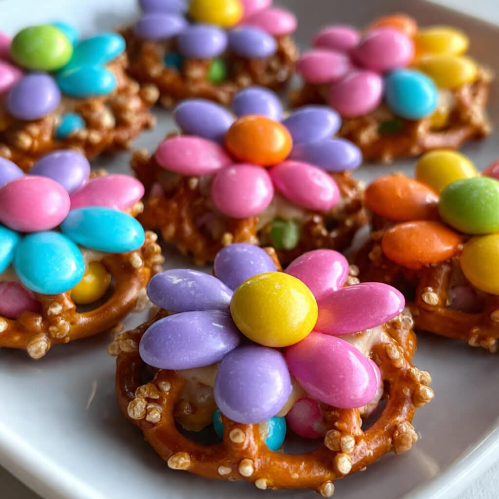 Flower Pretzel Bites 4 Colorful flower pretzel bites made with mini pretzels, pastel candy melts, and round candies arranged on white parchment paper