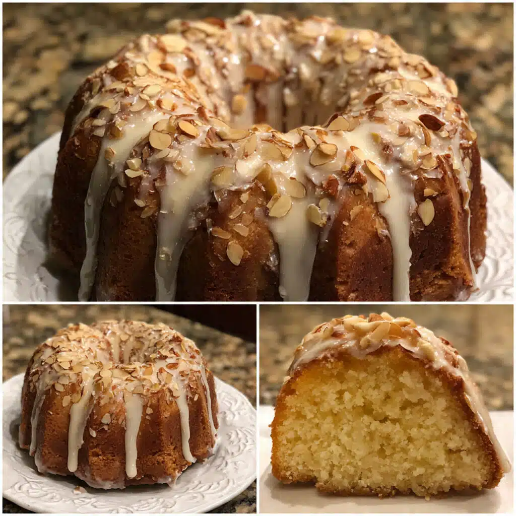 golden brown almond bundt cake on a white cake stand, drizzled with white almond glaze and topped with toasted sliced almonds, with one slice removed showing the moist, tender crumb