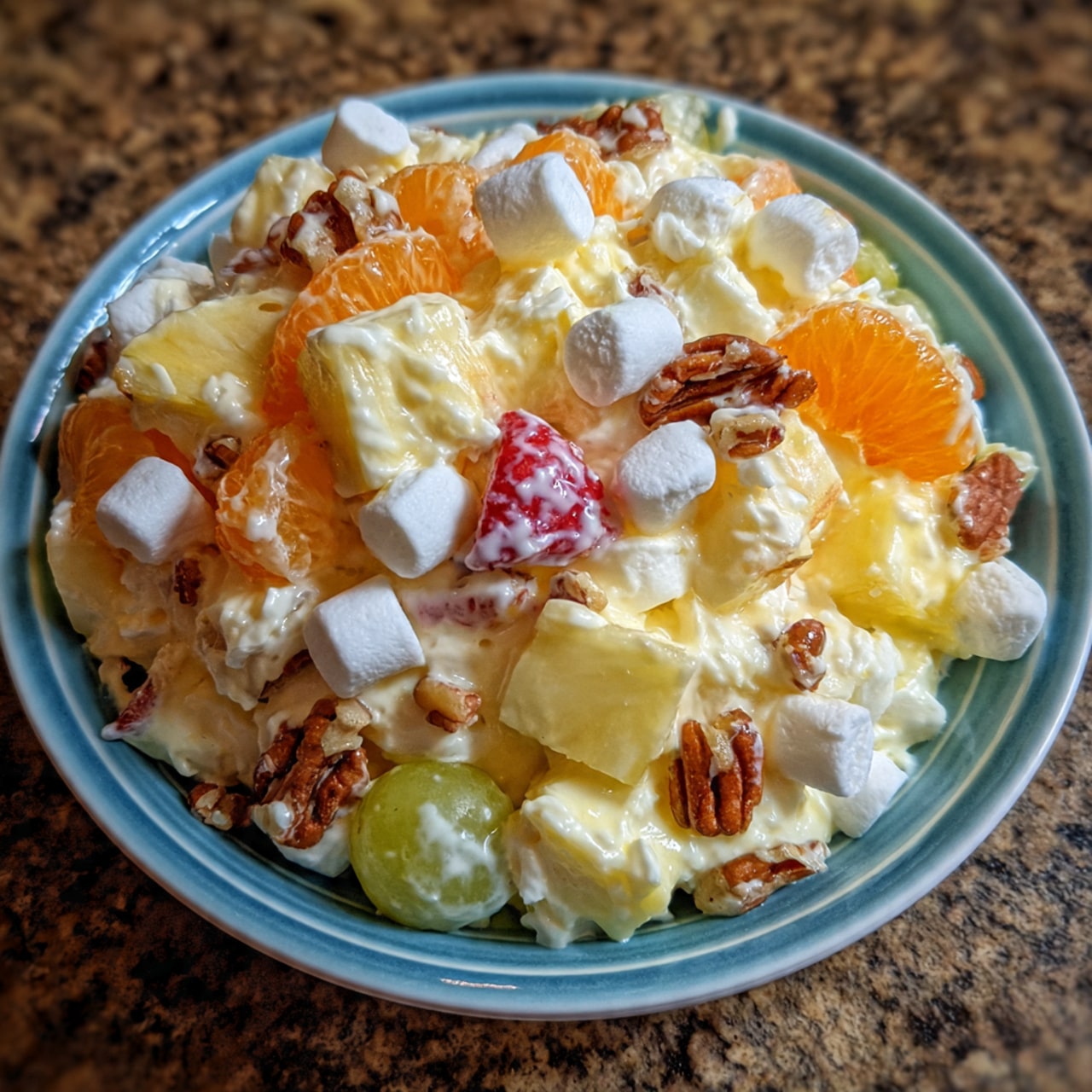 Easter ambrosia salad with pineapple chunks, mandarin oranges, marshmallows, and shredded coconut garnished with fresh strawberries
