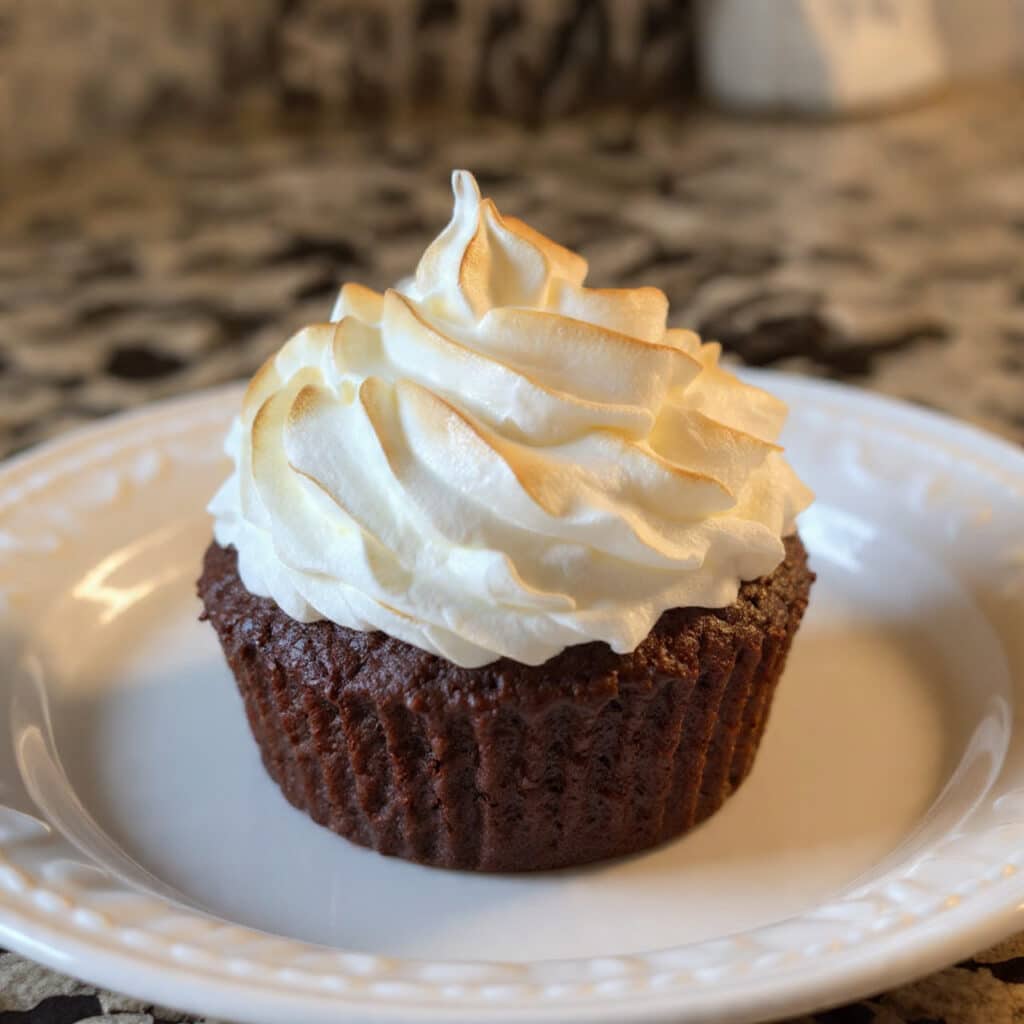 Fluffy white marshmallow cream frosting piped onto chocolate cupcakes in beautiful swirls