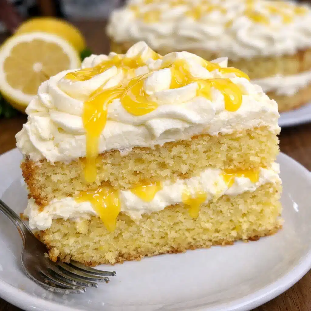 A slice of limoncello mascarpone cake on a white plate, showing moist yellow cake topped with fluffy white mascarpone frosting swirled with golden lemon curd